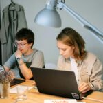 Two young professionals focus on a project together in a modern workspace.